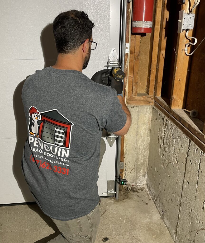 Penguin Garage Doors technician tightening hardware after completing garage door repairs in Vaughan.