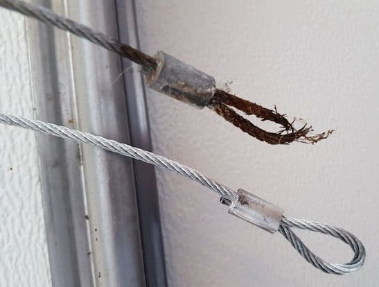 Comparison photo showing close ups of a rusted garage door cable with a broken loop next to a new cable in proper condition, highlighted by Penguin Garage Doors in Richmond Hill.
