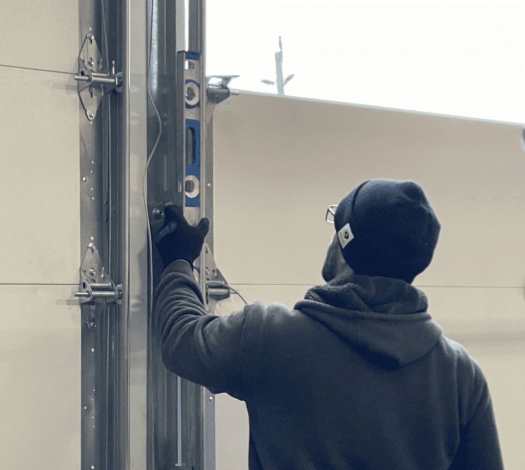 Garage door technician aligning garage door tracks to ensure smooth garage door operation in Thornhill by Penguin Garage Doors.