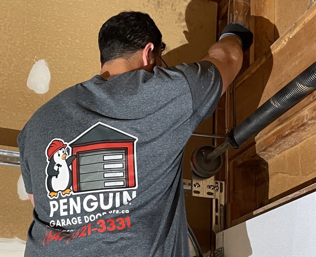 Garage door technician performing a garage door spring replacement for expert garage door service in Markham by Penguin Garage Doors.