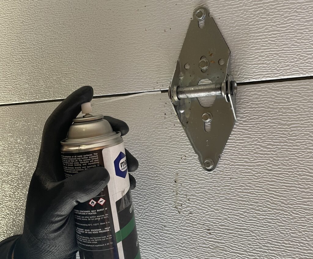 Penguin Garage Doors technician lubricating a garage door hinge during professional maintenance service in Thornhill.