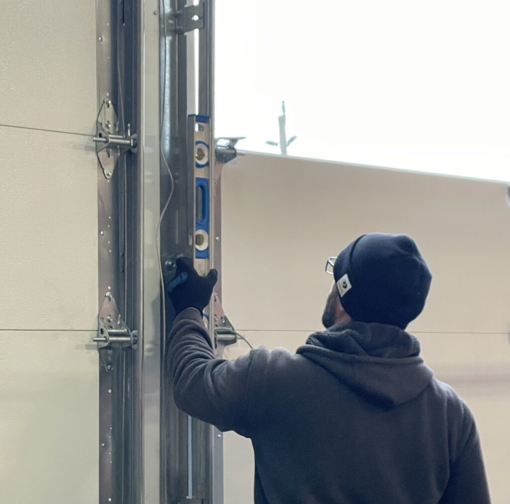 Penguin Garage Doors technician using a level to ensure garage door tracks are properly aligned and straight during professional garage door installation.