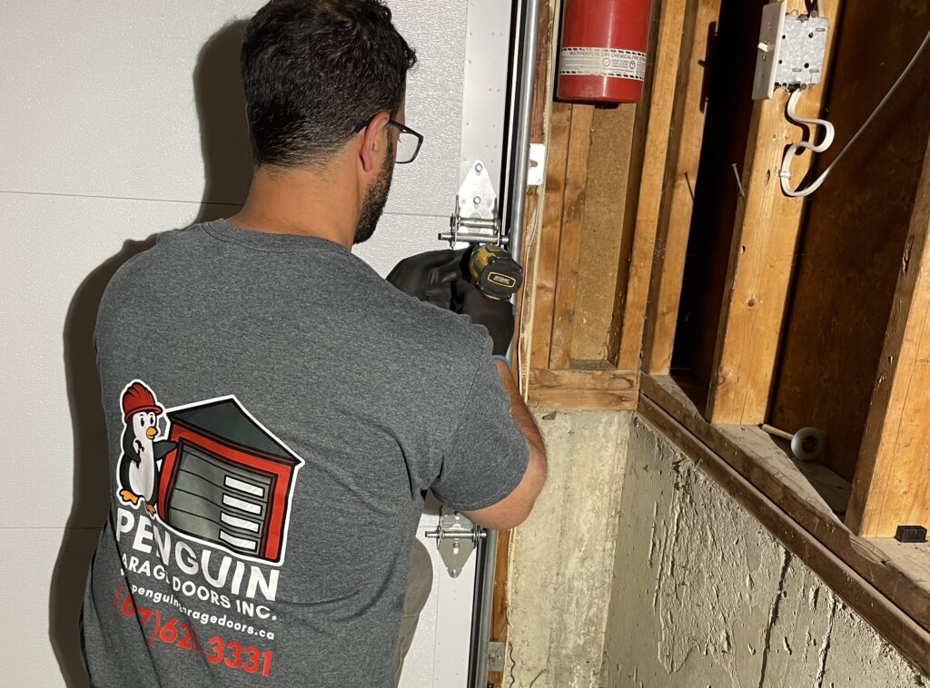 Penguin Garage Doors technician repairing garage door roller and garage door hinge as part of professional garage door repair services in Vaughan