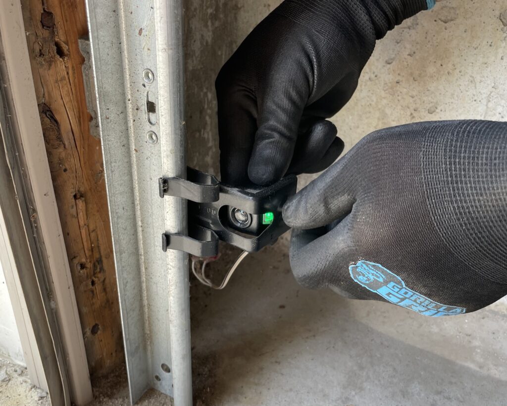 Penguin Garage Doors technician adjusting garage door opener sensors during routine maintenance for safe and reliable operation.
