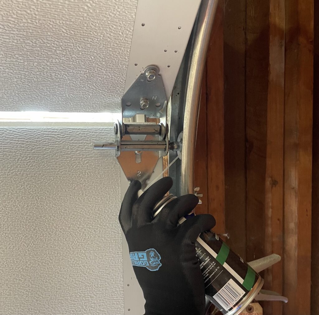 Penguin Garage Doors technician lubricating garage door rollers during maintenance to ensure smooth and quiet door operation.
